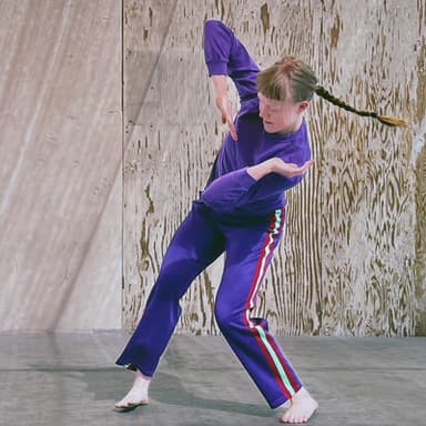 Chelsea Reichert, wearing purple, twists her arms and torso while her braid swings out to the opposite side.