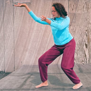 Shareen DeRyan, wearing turquoise and maroon, places her hands in the air with specificity.