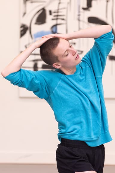 Headshot of Emily Hansel wearing a turquoise sweater grabbing her head